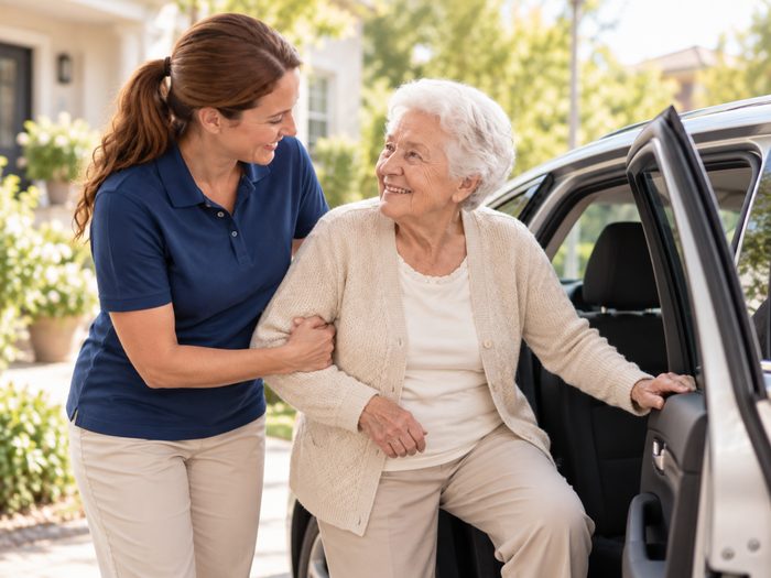 Betreuungskraft hilft Seniorin beim Einstieg ins Auto