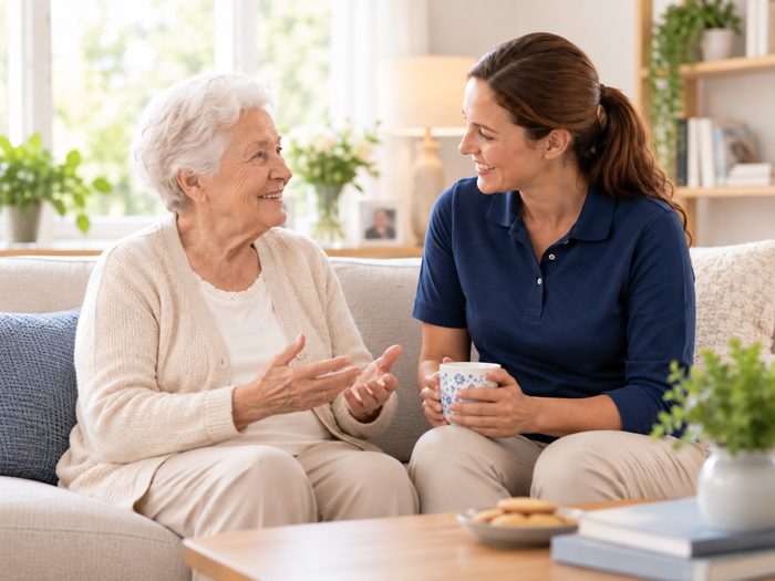 Seniorin im Gespraech mit ihrer Betreuungskraft bei Kaffee und Keksen